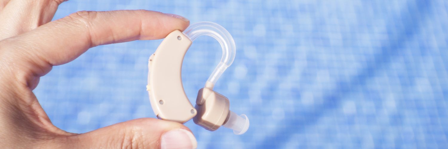 32850484_womans-hand-holding-hearing-aid